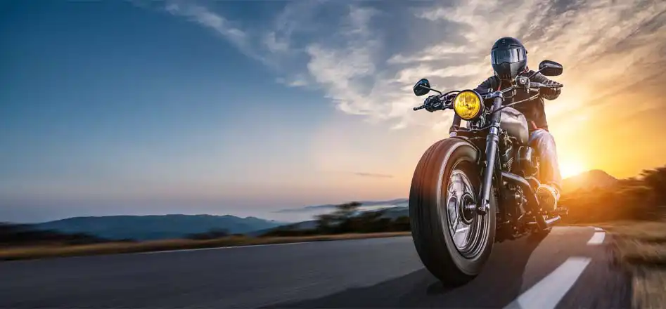 Electroquest Motorcycle Batteries and Accessories. Photo of a motorcyclist riding at sunset.