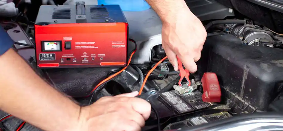Battery Chargers Store from Electroquest. Photo of a person using a battery charger on their car battery.
